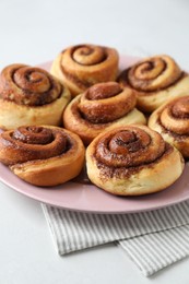 Photo of Many tasty cinnamon rolls on white table, closeup