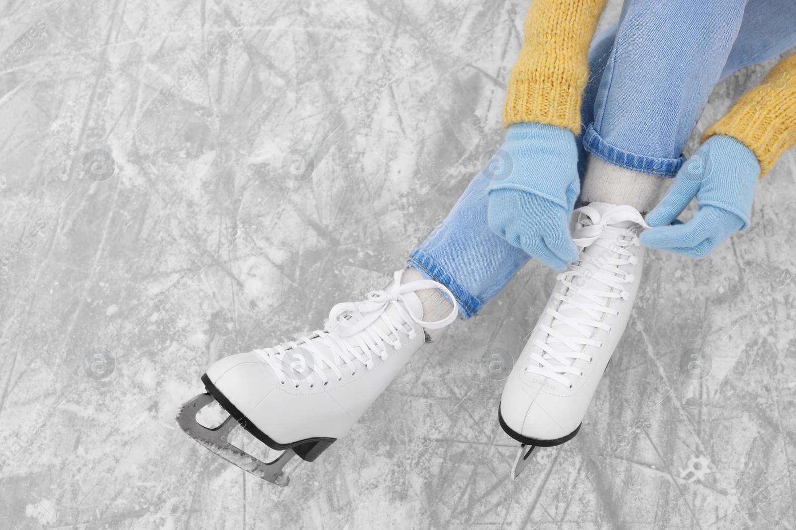 Photo of Woman lacing figure skates on ice, top view. Space for text