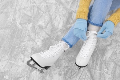 Photo of Woman lacing figure skates on ice, top view. Space for text