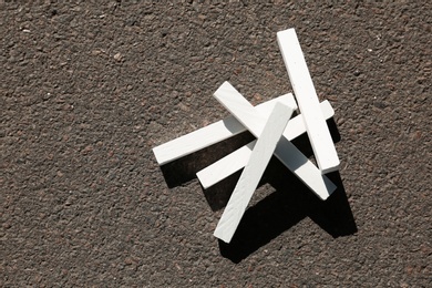 Photo of White chalk sticks on asphalt, top view