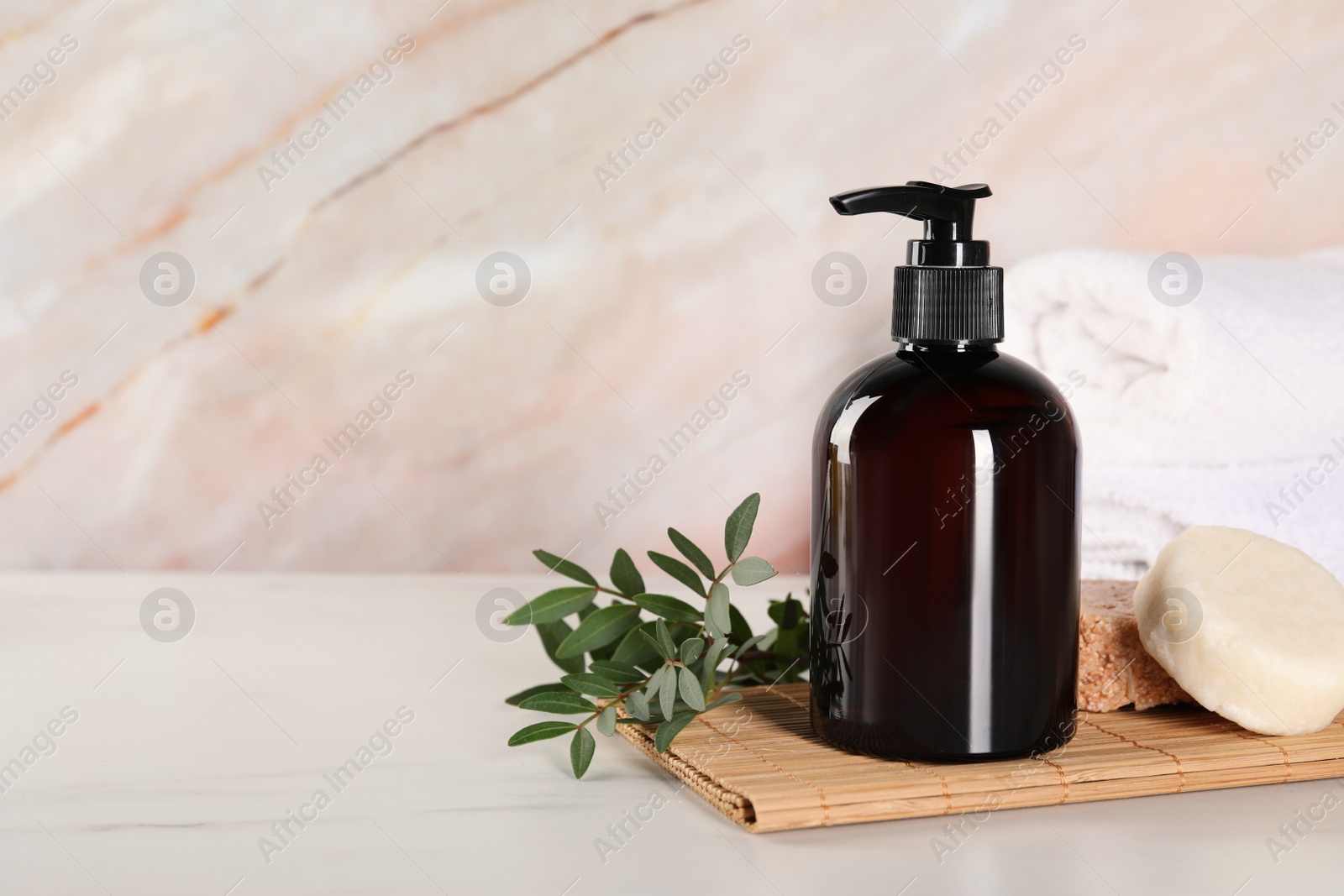 Photo of Shampoo bottle, solid shampoo bars and folded towels on white marble table, space for text