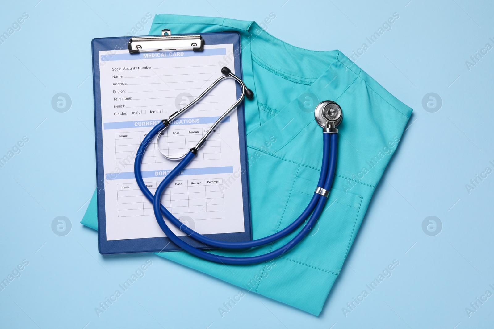 Photo of Medical uniform, stethoscope and clipboard on light blue background, flat lay