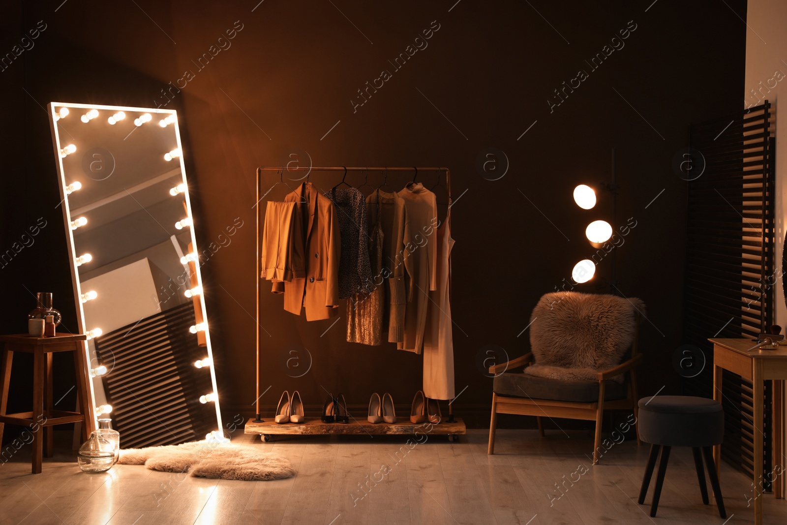 Photo of Stylish mirror with light bulbs and comfortable armchair in dressing room. Interior design