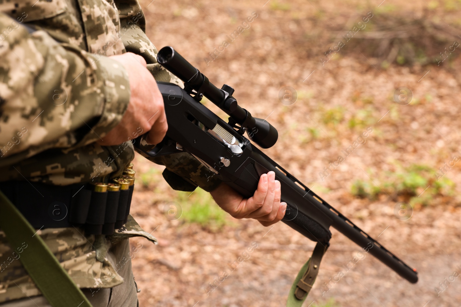 Photo of Man with hunting rifle wearing camouflage outdoors, closeup