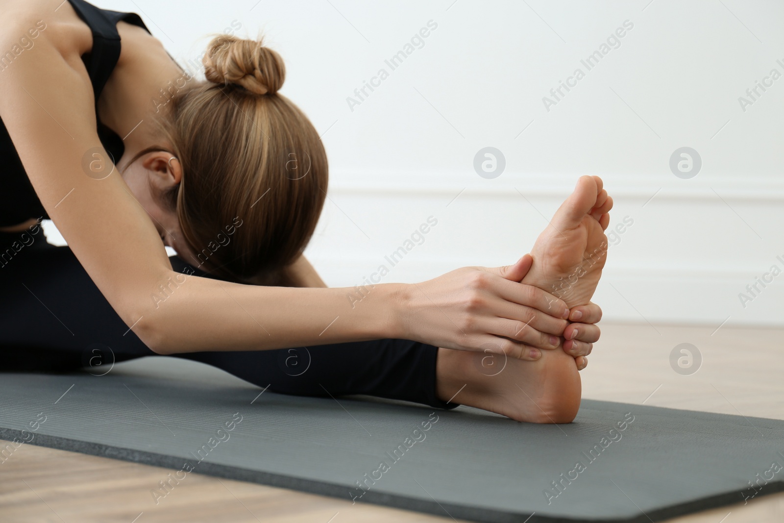 Photo of Young woman practicing head to knee asana in yoga studio. Janu Sirsasana pose