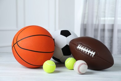 Set of different sport balls on white wooden table indoors