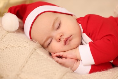 Cute baby in Christmas costume sleeping on knitted blanket, closeup. Winter holiday