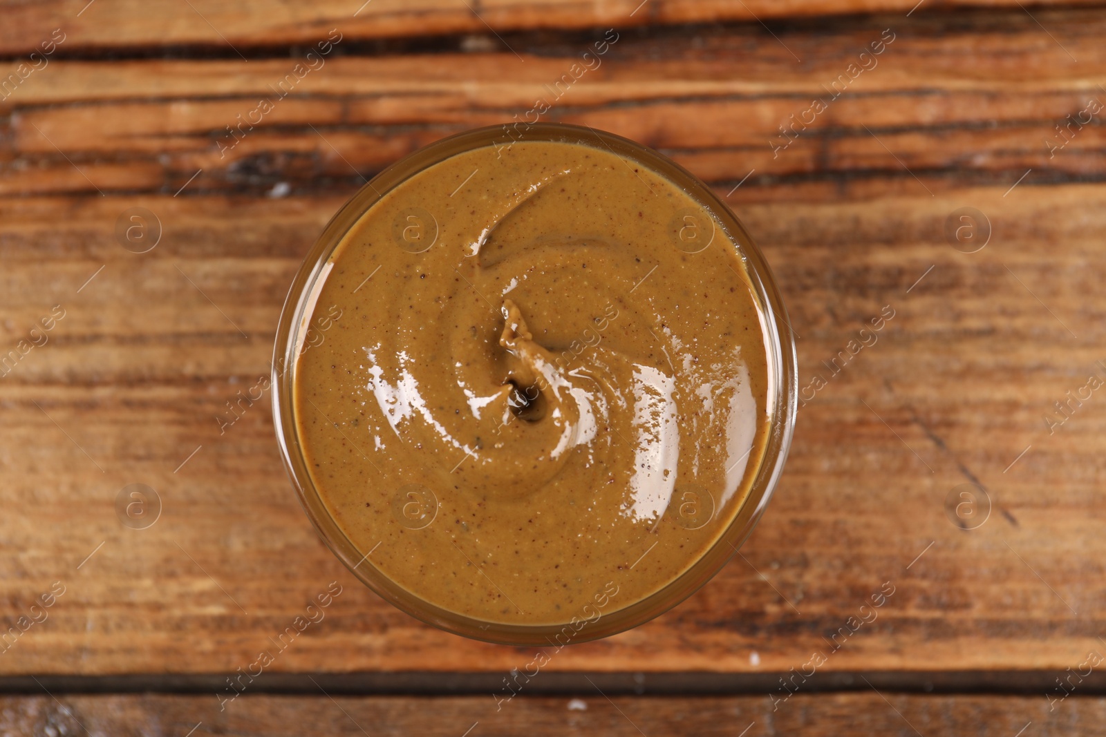 Photo of Delicious nut butter in bowl on wooden table, top view