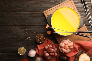 Flat lay composition with oil pot, meat fondue ingredients and space for text on wooden background