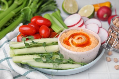 Plate with delicious hummus and fresh vegetables on table