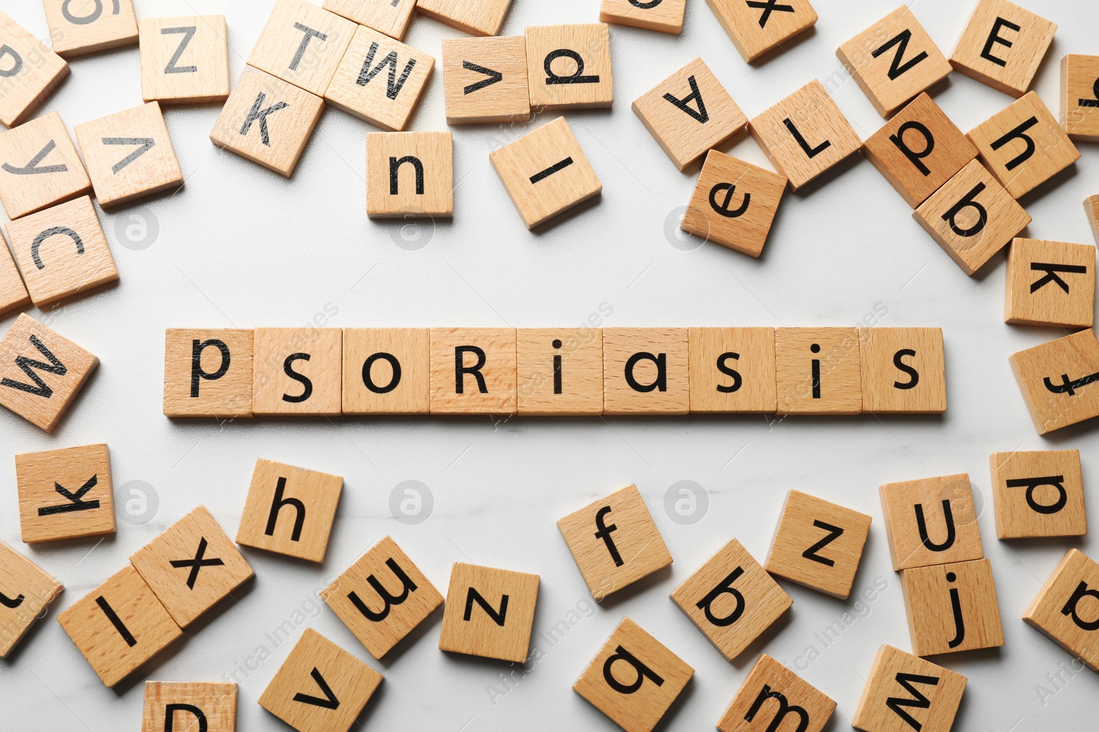 Photo of Word Psoriasis made of wooden squares with letters on white table, flat lay