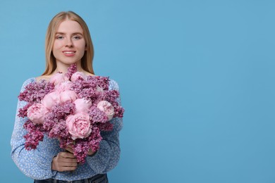 Photo of Beautiful woman with bouquet of spring flowers on light blue background, space for text