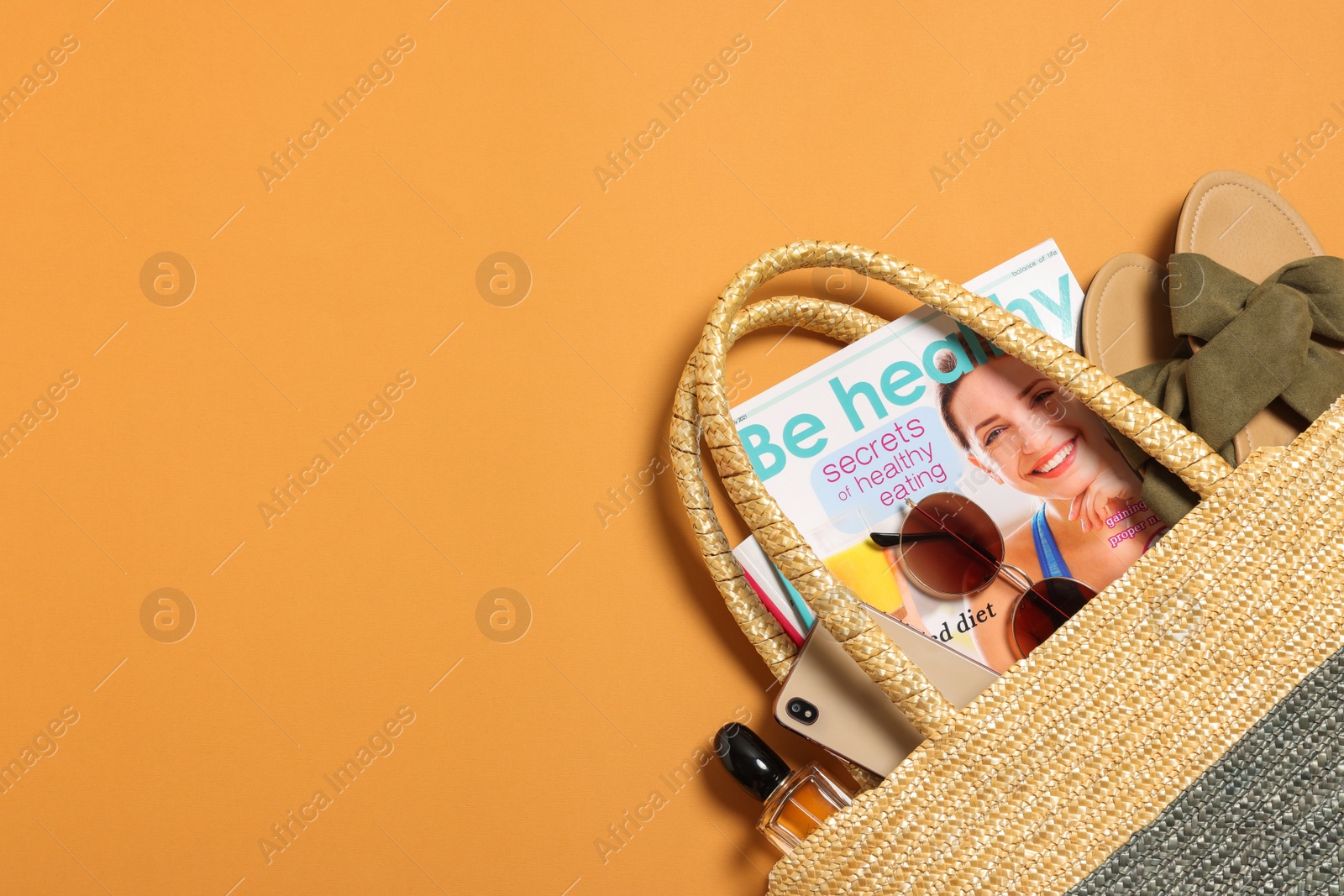 Photo of Flat lay composition with wicker bag and other beach accessories on orange background. Space for text