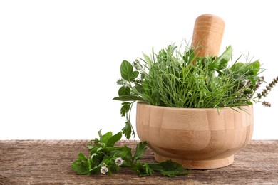 Mortar, pestle and different herbs on wooden table against white background. Space for text