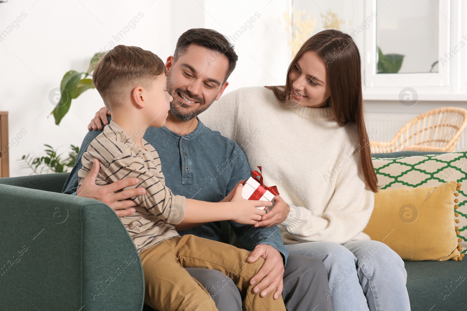 Photo of Happy family with gift on sofa at home