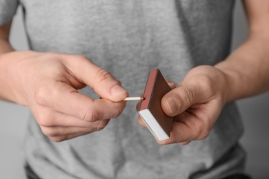 Man with box of matches on grey background, closeup