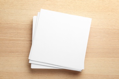 Photo of Stack of blank paper sheets for brochure on wooden background, top view. Mock up