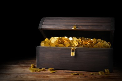 Open treasure chest with gold coins on wooden table