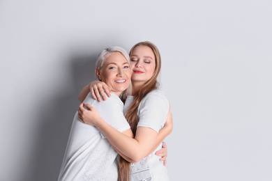 Mother and her adult daughter on white background. Space for text