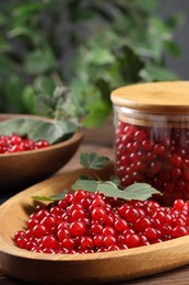 Photo of Ripe red currants and leaves on wooden table, closeup. Space for text