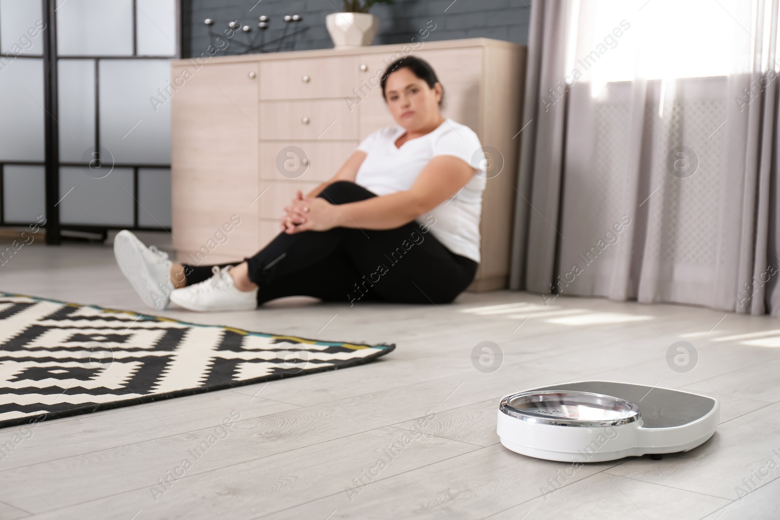 Photo of Scales and overweight woman in sportswear on background