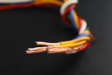 Photo of Many twisted electrical cables on black background, closeup
