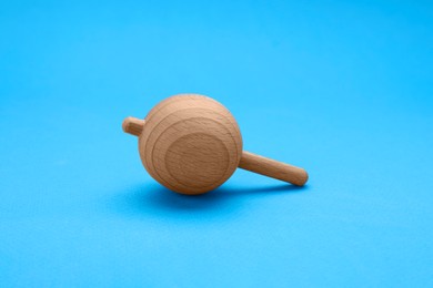 Photo of One wooden spinning top on light blue background. Toy whirligig