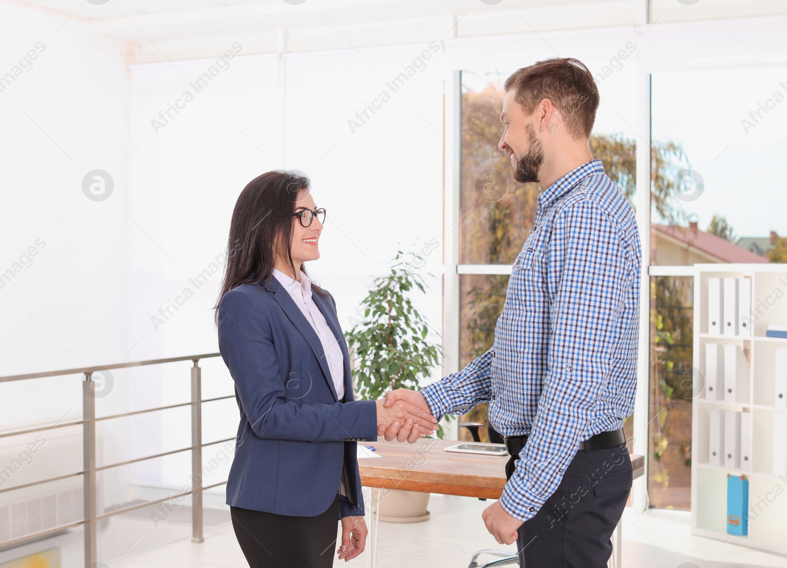 Photo of Human resources manager shaking hands with applicant during job interview in office