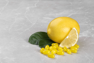 Photo of Tasty candy drops and fresh lemon on grey marble table