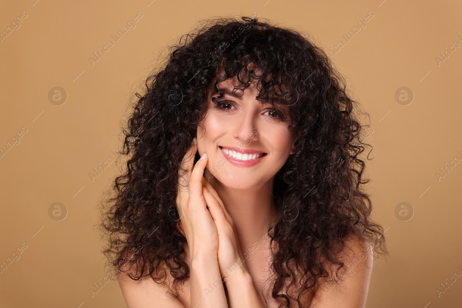 Photo of Beautiful young woman with long curly hair on beige background