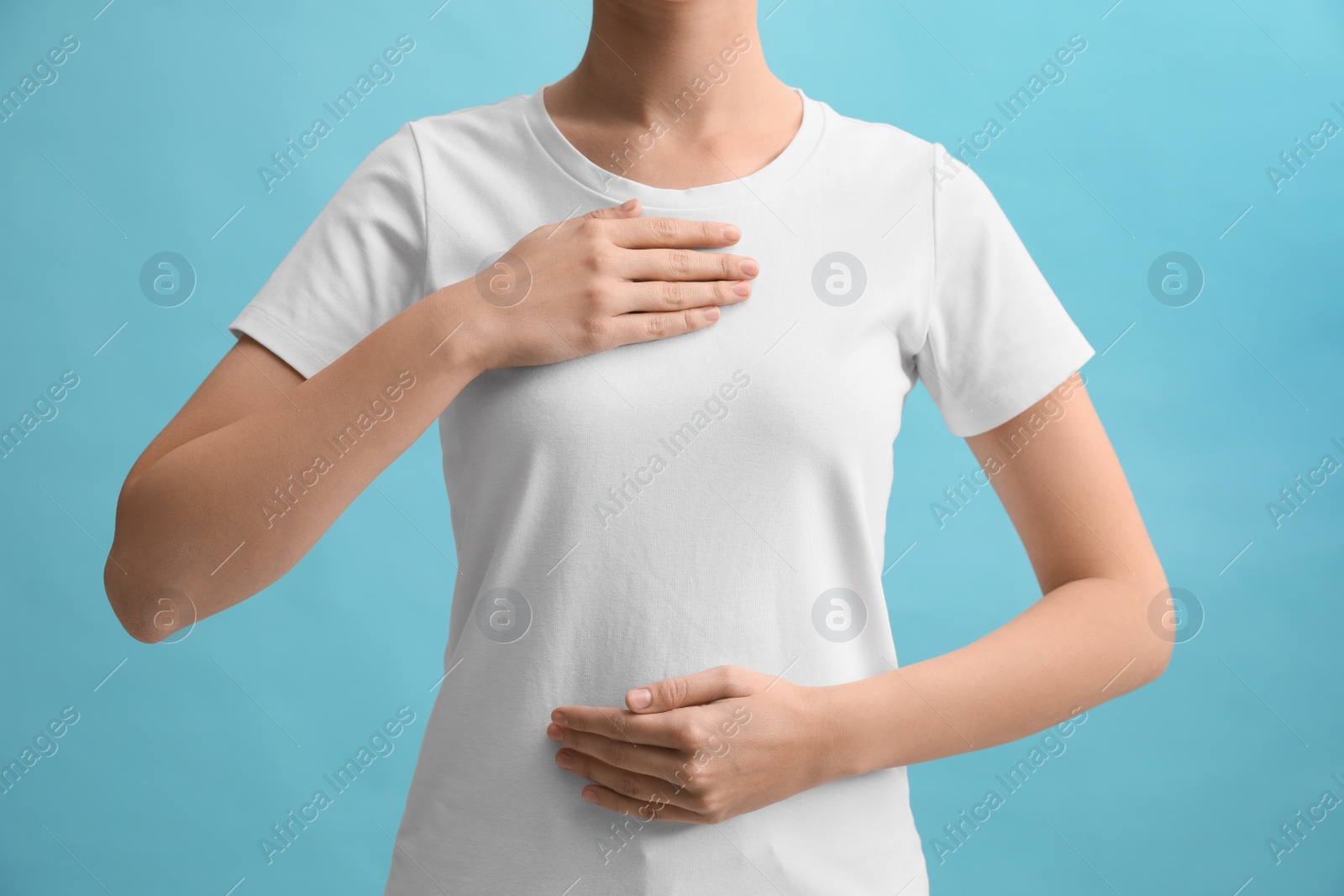 Photo of Woman holding hands near chest on turquoise background, closeup