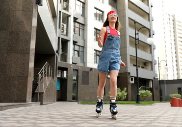 Beautiful young woman with roller skates having fun outdoors, space for text