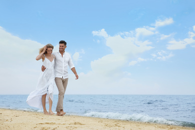 Photo of Happy couple having romantic walk on beach. Space for text