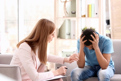 Young female psychologist working with teenage boy in office