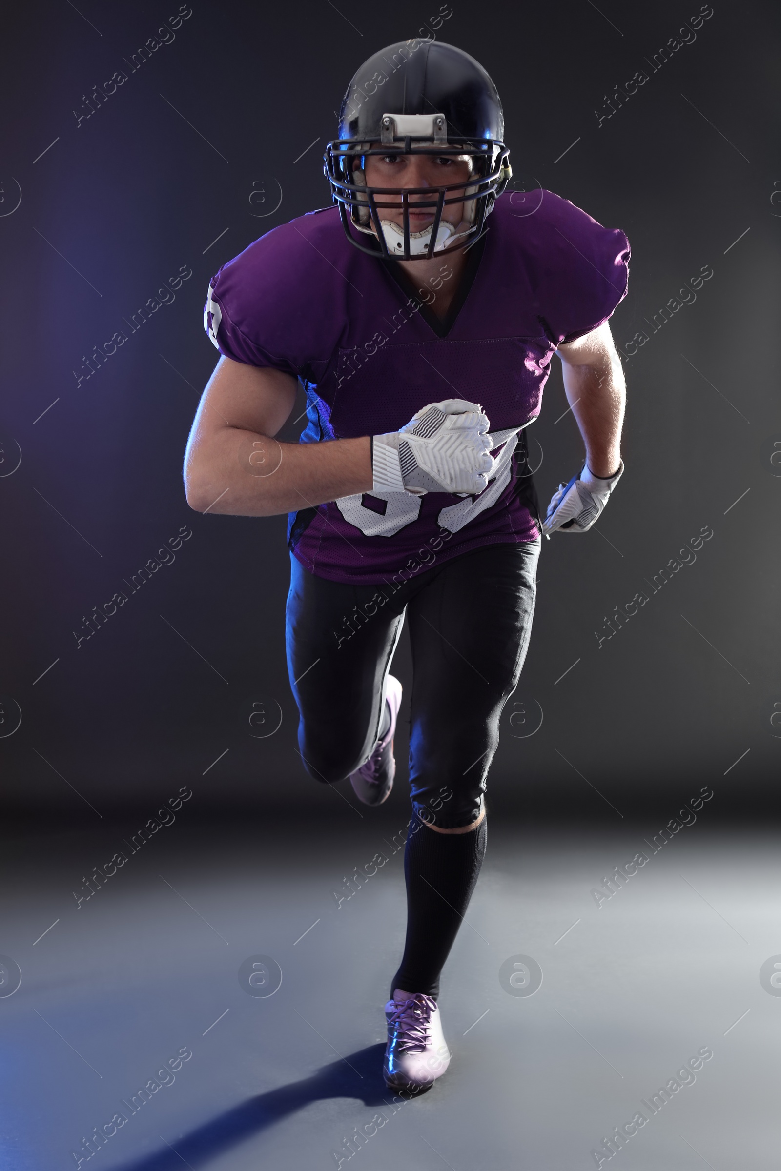 Photo of American football player wearing uniform on dark background