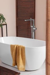 Photo of Stylish bathroom interior with ceramic tub and terry towel