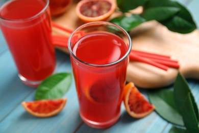 Photo of Tasty sicilian orange juice and fruits on light blue wooden table