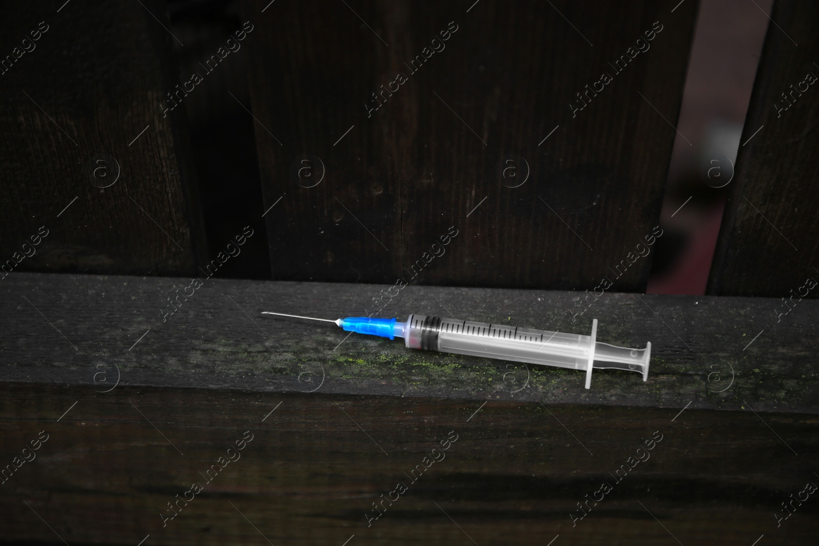 Photo of Empty syringe on surface of wooden fence outdoors