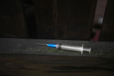 Empty syringe on surface of wooden fence outdoors