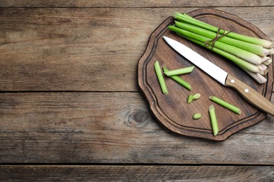 Fresh lemongrass, knife and cutting board on wooden table, top view. Space for text