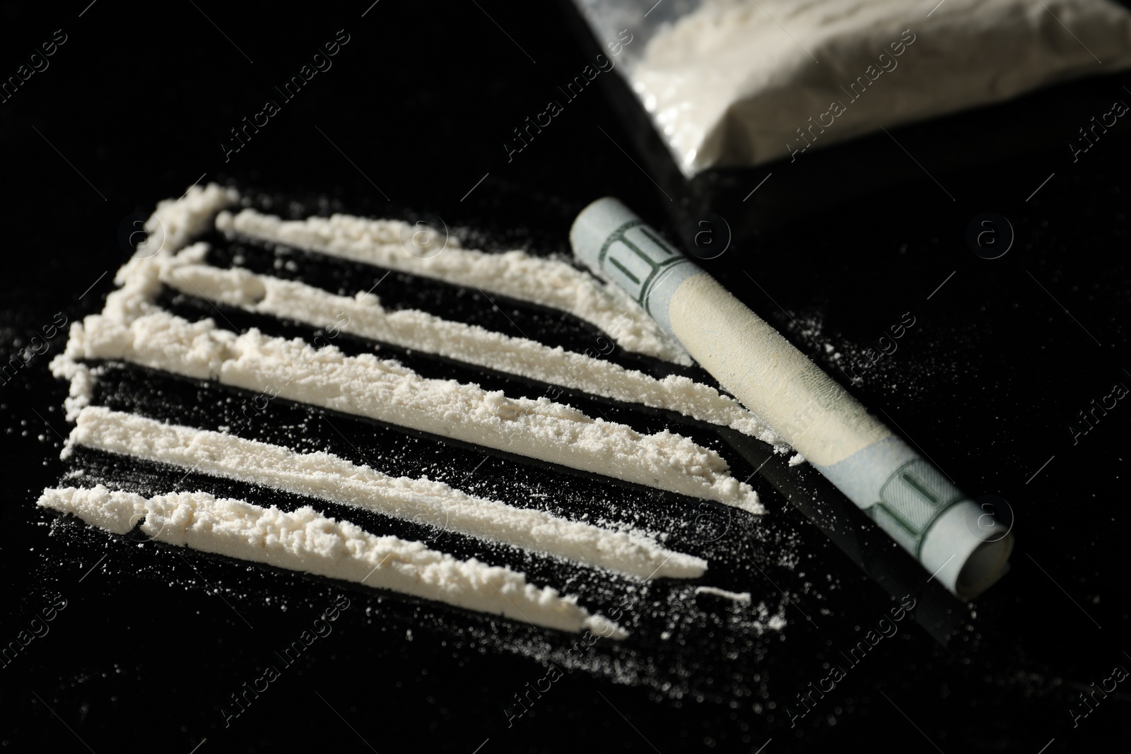 Photo of Drug addiction. Cocaine and rolled dollar banknote on black table, closeup