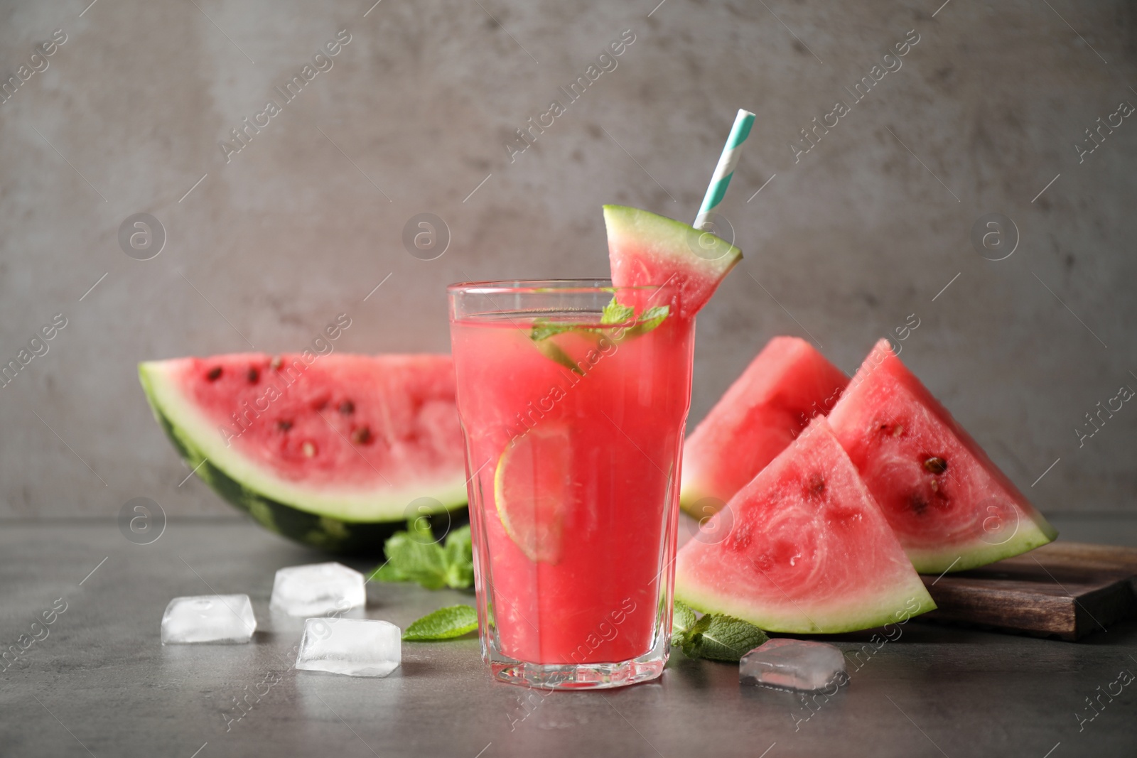 Photo of Glass of tasty refreshing drink with watermelon on grey table