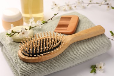 Photo of Wooden hairbrush, comb, cosmetic products and branch with flowers on white background