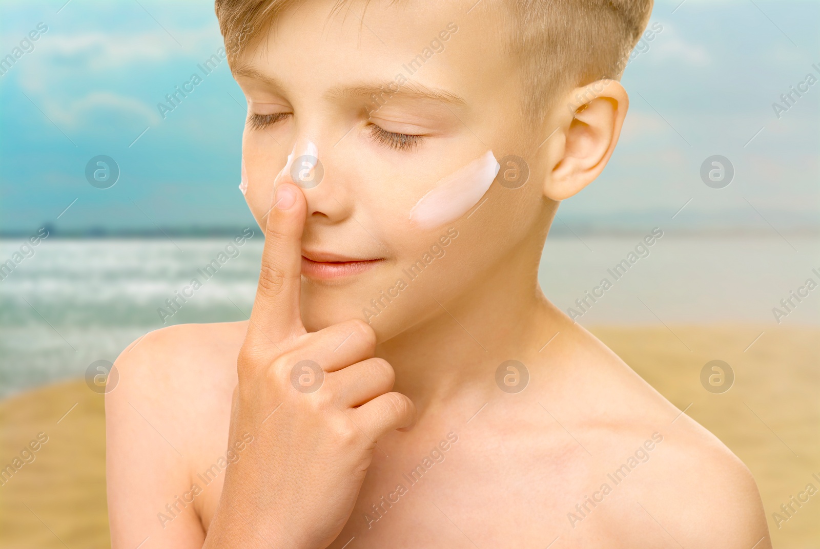 Image of Sun protection. Boy applying sunblock onto face on beach, closeup