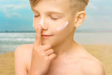 Sun protection. Boy applying sunblock onto face on beach, closeup