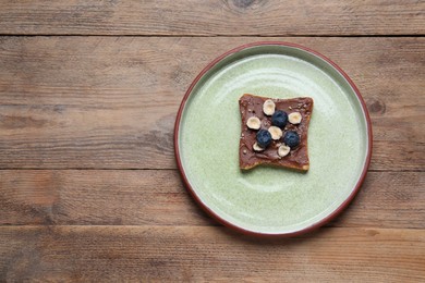 Toast with tasty nut butter, jam, blueberries and nuts on wooden table, top view. Space for text
