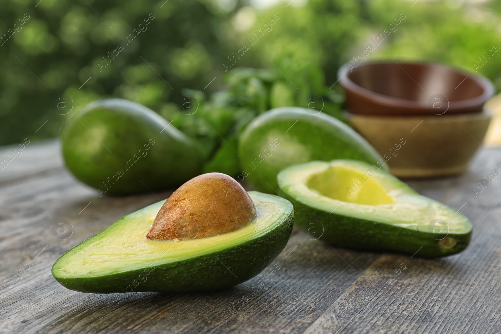 Photo of Ripe avocados on wooden table against blurred background