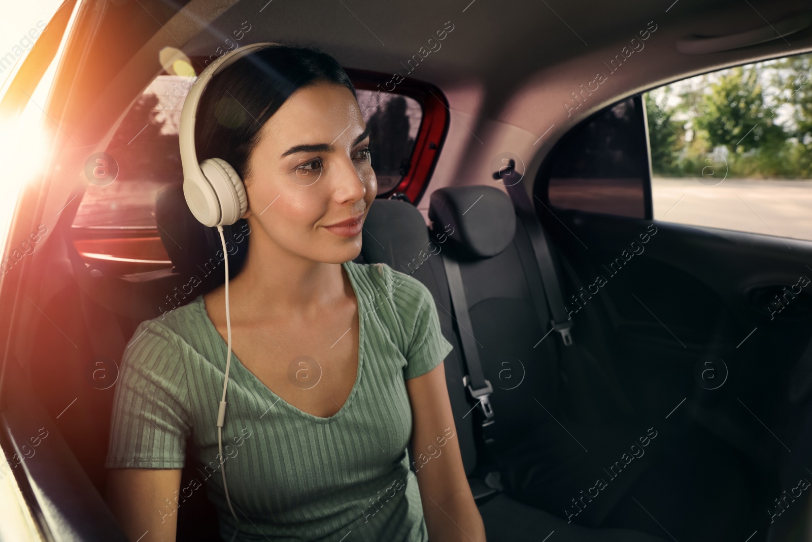 Photo of Young woman listening to music in modern taxi, space for text