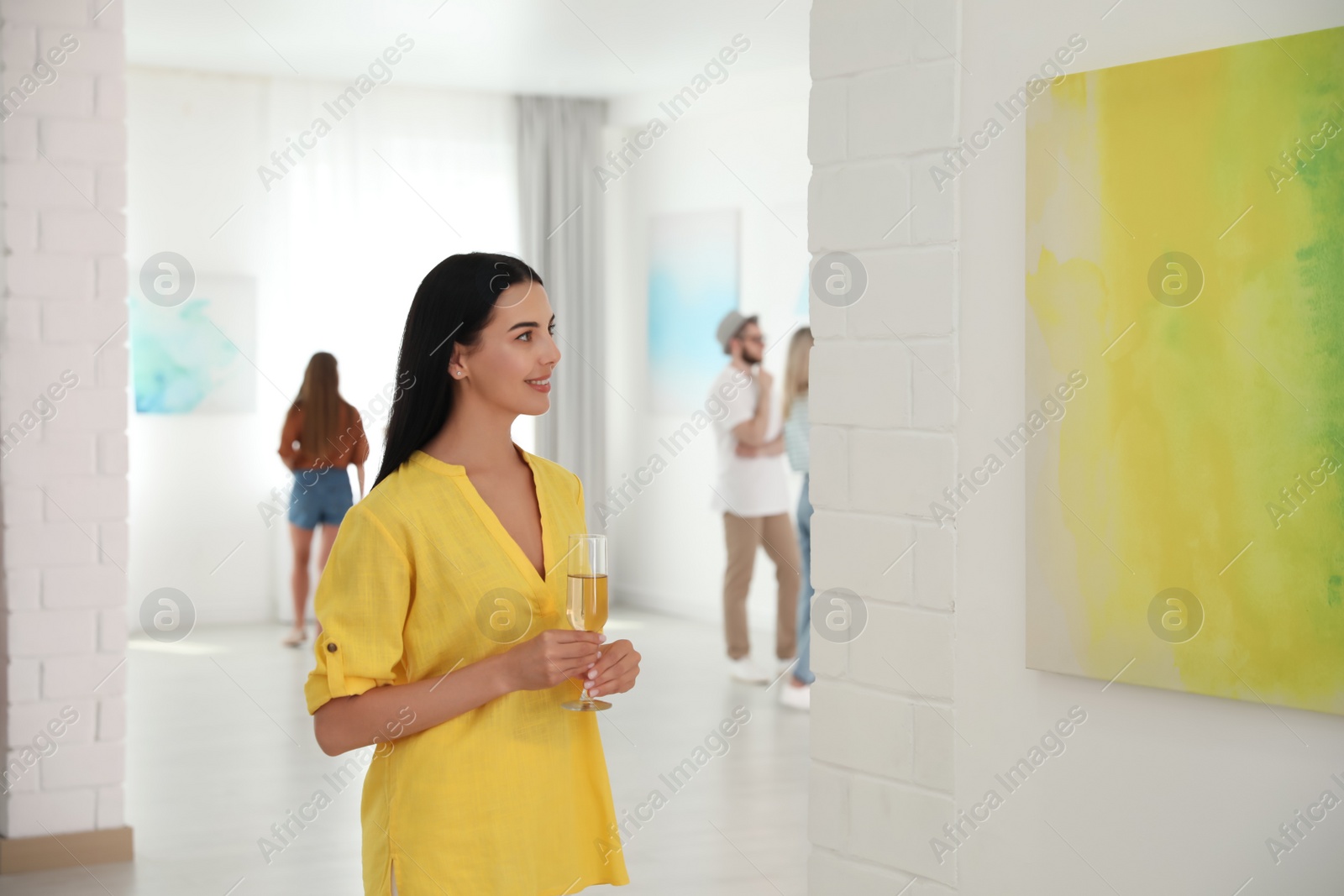 Photo of Young woman with glass of champagne at exhibition in art gallery