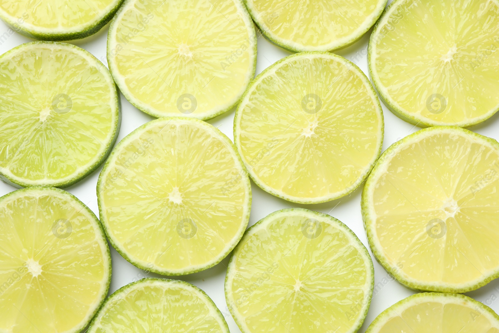 Photo of Fresh juicy lime slices on white background, flat lay